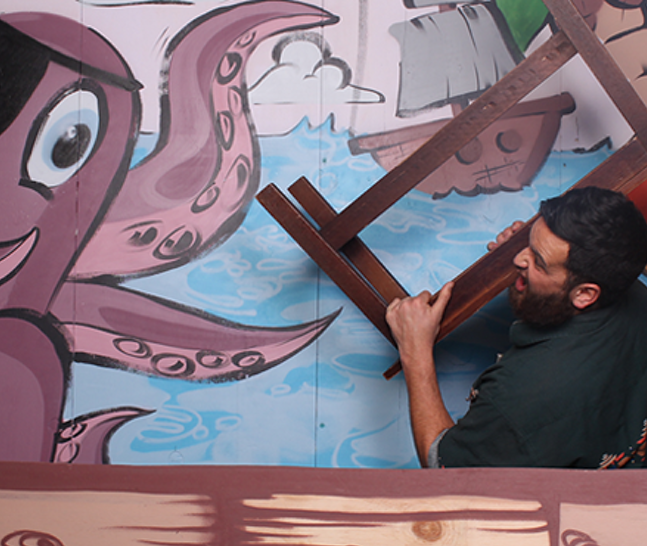 Wellington photobooth host Max poses in front of the giant painted octupus backdrop